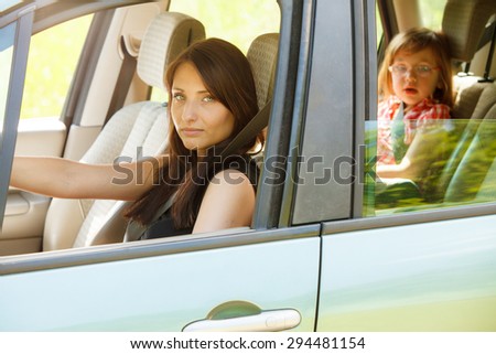 Road transportation and safety. Mother female driver and daughter little girl child kid sitting in car seat.