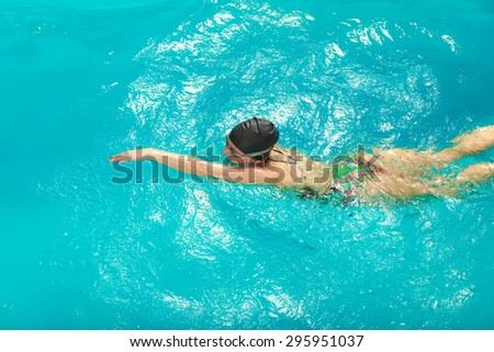 Woman athlete swimming performing crawl style stroke in pool. Active human swimmer taking breath. Water sport comptetition.