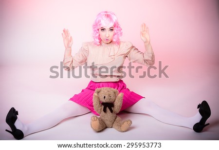 Mental disorder concept. Young childlike woman wearing like puppet doll holding teddy bear toy studio shot