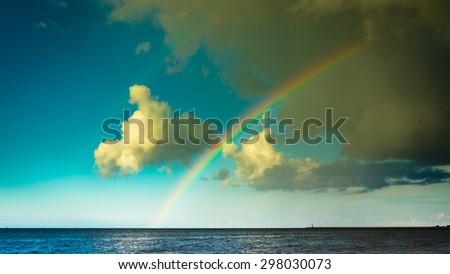 landscape view on cloudy sky with colorful rainbow at sea or ocean outdoor. Weather.