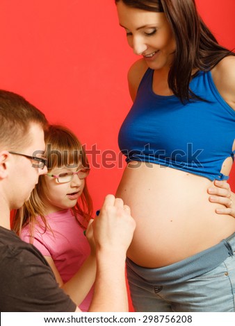 Pregnancy, parenthood and happiness concept. Family expecting new baby, having fun, drawing painting on belly of pregnant woman