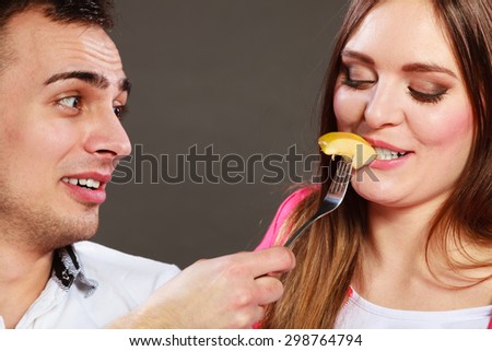 Smiling man feeding happy woman with apple. Wife and husband eating fruit. Healthy nutrition, dieting and slimming concept.