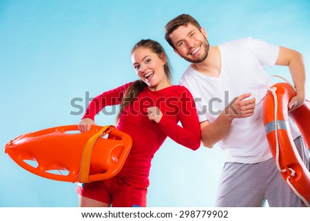 Accident prevention and water rescue. Young man and woman lifeguard couple on duty holding buoy lifesaver equipment having fun on blue