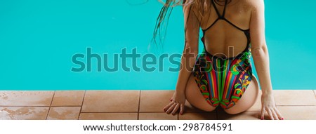 Relax, rest and recreation. Long haired woman back in colorful swimsuit on pool edge.