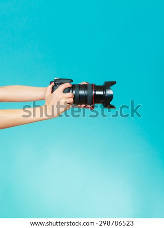 Photographer girl shooting images. woman hands holding camera taking photos. Vivid blue background