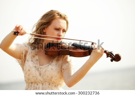 Portrait of blonde girl music lover on beach playing the violin. Love of music concept.