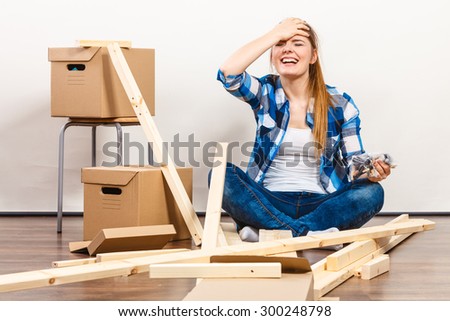 Worried woman moving into new apartment house assembling. Young girl holding screws and furniture parts arranging interior and unpacking boxes.