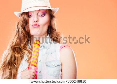 Summer vacation happiness concept. Funny crazy woman in straw hat cross eyed eating popsicle ice cream orange background