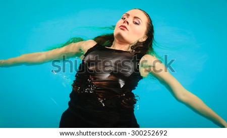 Woman relaxing at swimming pool. Young girl wearing black dress floating. Water aerobics fitness.