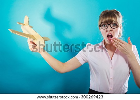 Fly fear metaphor, aerophobia concept. Business woman holding airplane in hand vivid blue background