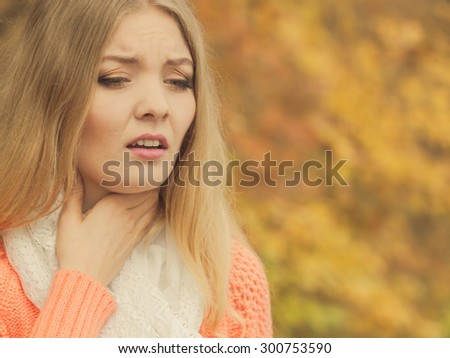 Sick woman in fall autumn park. Ill girl caught cold flu outdoor. Rhinitis or allergy. Health care.