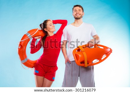 Accident prevention and water rescue. lifeguard couple on duty woman leaning on man arm, holding buoy lifesaver equipment on blue