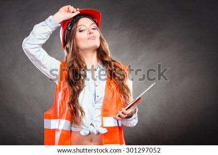 Sexy alluring woman structural engineer wearing helmet holding tablet computer. Strong girl feminist working in man profession. Independent female.