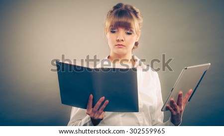 Woman learning with ebook reader and book. Choice between modern educational technology and traditional way method. Girl holding digital tablet and textbook. Contemporary education. Instagram filter.