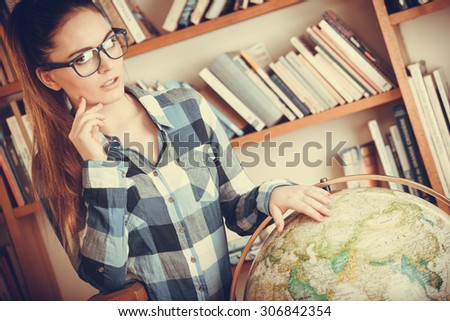 Education travel and geography concept. Hipster lovely woman female student in blue glasses in library with globe. Instagram filter