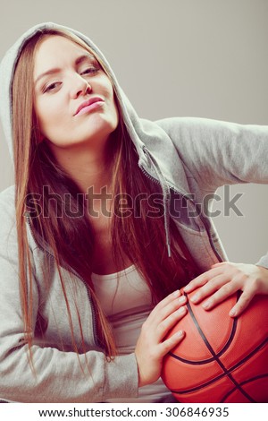 Funny sporty teenager girl wearing hooded sweatshirt holding basketball. Teen sport. Face expression.