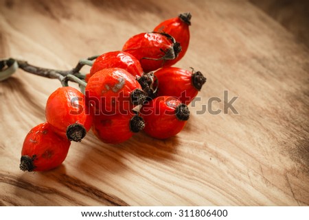 Hawthorn on wooden rustic table background. Rose hips haw fruit of the dog rose.