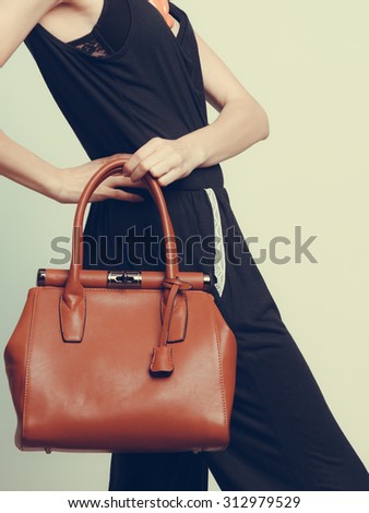 Elegant fashionable woman with leather handbag. Stylish girl holding brown bag. Female fashion vogue. Studio. Instagram filter.