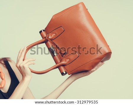 Elegant fashionable woman with leather handbag. Stylish girl holding brown bag. Female fashion vogue. Studio. Instagram filter.