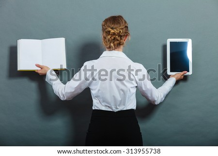 Ebook vs book. Woman female student holding traditional book and e-book reader tablet touchpad pc back view grunge background.