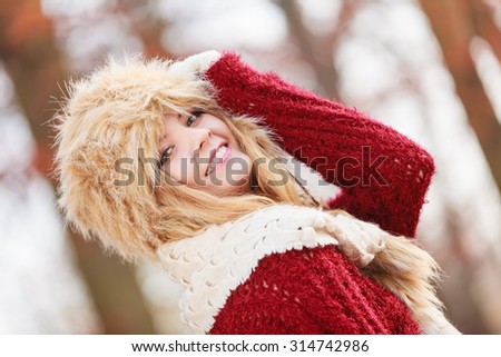 Pretty woman in fall forest park. Gorgeous young girl in fur winter hat and sweater. Autumn fashion.