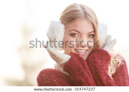 Portrait of pretty smiling fashionable woman in fall forest park. Happy gorgeous young girl in white earmuffs and sweater pullover. Autumn winter fashion.
