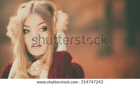 Portrait of pretty attractive fashionable woman in fall forest park. Gorgeous young girl in earmuffs and maroon sweater pullover. Autumn winter fashion. Instagram filter.