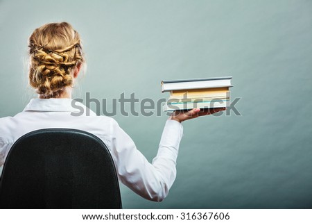 Education school or business concept. Woman female student sitting on chair holding stack books. Back view grunge background