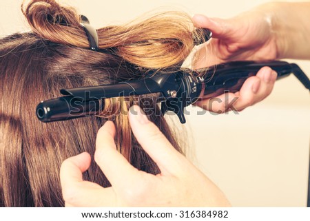 Stylist curling hair for young woman. Girl care about her hairstyle