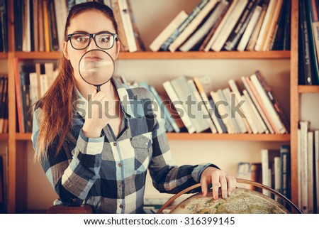 Education travel and geography concept. Young clever woman female student in blue glasses in library with globe and magnifying glass. Instagram filter