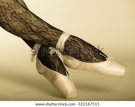 beautiful woman ballet dancer, part of body legs in shoes and black lace tights studio shot vintage aged tone