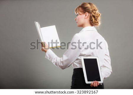 Woman learning with book holding ebook reader behind back. Choice between modern educational technology and traditional way method. Girl hold digital tablet pc and textbook. Contemporary education.