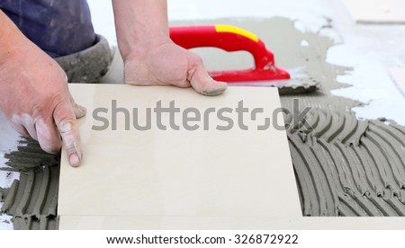 Home improvement, renovation - construction worker tiler is tiling, ceramic tile floor adhesive, trowel with mortar