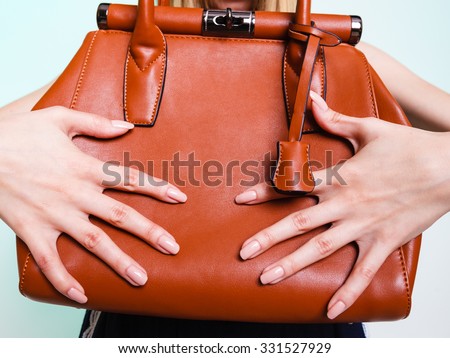 Closeup woman holding brown leather handbag bag. Fashion and female beauty.