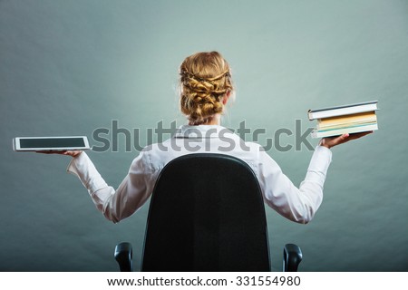 Ebook vs book. Woman sitting on chair holding traditional book and e-book reader tablet touchpad pc back view grunge background.