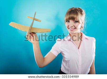 Summer holidays and tourism concept. attractive business woman enjoying life daydreaming thinking about vacation holding paper toy airplane in hand on blue