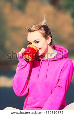 Young pretty girl at park drinking hot tea in mug. Woman care about health sitting on fresh air.