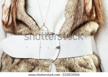 Winter time fashion for women. Woman wearing sweater fur vest belt and pendant in freezing cold time.