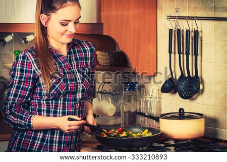Woman in kitchen cooking stir fry frozen vegetables. Girl frying making delicious risotto. Dinner food meal. Instagram filter.
