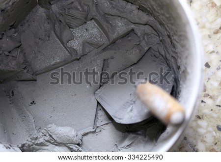 Old dirty trowel and bucket with mortar on construction building site