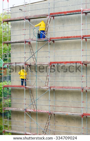 Men cleaning wall. Scaffolding, construction site in progress. Building renovation. Cleaning dirtiness.