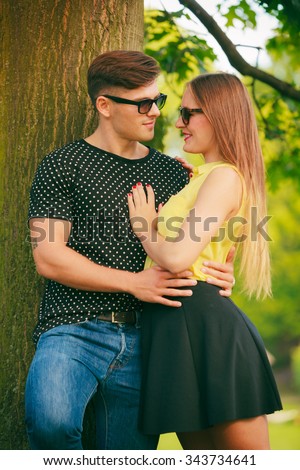 Love and happiness. Young happy couple lovers wearing sunglasses dating in summer park outdoor.