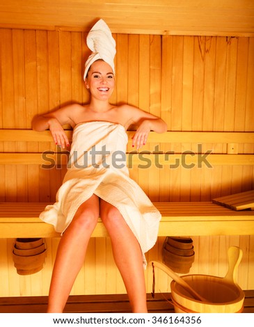 Spa beauty well being and relax concept. Woman in full length white towel sitting relaxed in wooden sauna