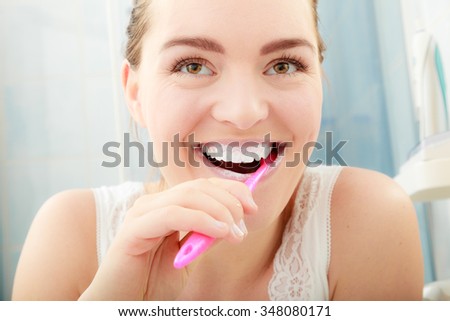 Young woman brushing cleaning teeth. Girl with toothbrush in bathroom. Oral hygiene.