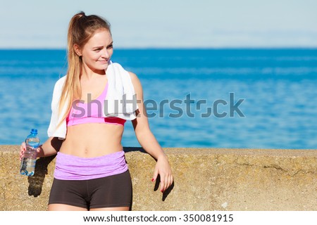 Health and body care idea. Sporty fit attractive woman with bottle of water after exercising workout outdoor.