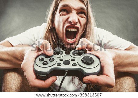 Addiction. Stressed depressed young man playing gaming on pad. Angry guy with controller pad play console. Face expression.