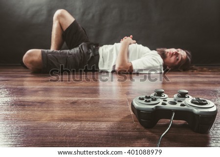 Addiction and dependency concept. Young man with pad joystick playing games. Male addicted to console videogames.