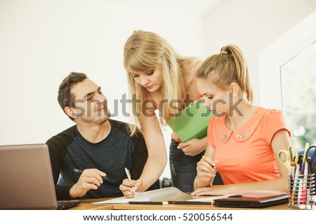 Teaching Concept. Female young teacher or tutor with adult students in classroom with papers, laptop computer. Studies course