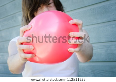 Woman squeezing red balloon in tension, ready to pop