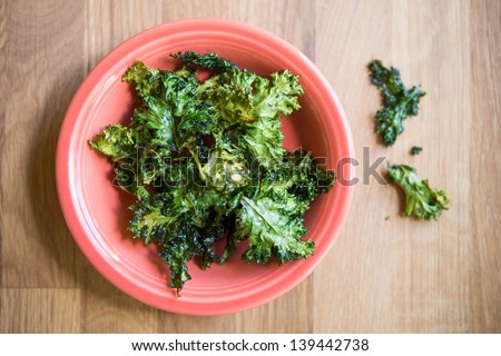 Baked Kale Chips with Olive Oil and Sea Salt in an Orange Bowl